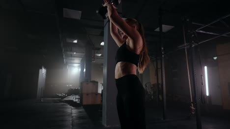 woman-is-training-with-weights-in-gym-lifting-and-throwing-up-dumbbell-working-in-fitness-center